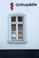 Orthopedic clinic signage (in german: Orthopaedie) with window reflections in a quiet urban setting...