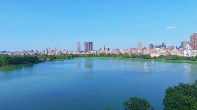 Upper East Side View From Jacqueline Kennedy Onassis Reservoir With Fountain At Central Park In Manhattan, NYC. wide drone shot