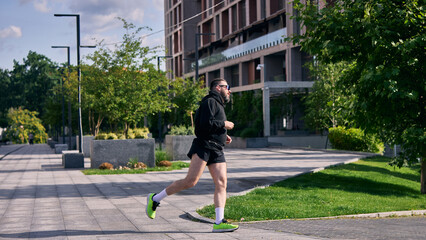 Middle aged man running in city park on sunny day. Concept of health commitment, early routine,...