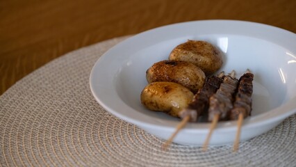 Roasted potatoes and grilled beef skewers on white plate