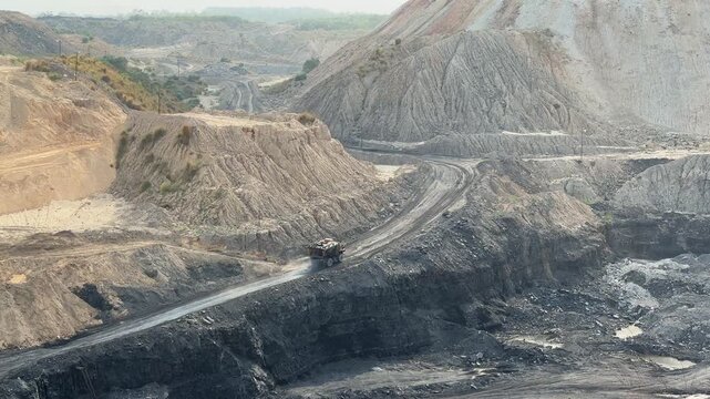 A large mining dump truck is spraying water on the roads inside coal mines for dust suppression and to mitigate the health hazards associated with airborne dust and maintain safe working conditions