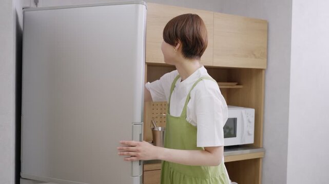冷蔵庫からペットボトルの飲み物を取り出す女性