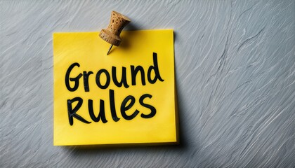 a yellow sticky note pinned to a textured gray wall displays the handwritten phrase "ground rules" in bold black marker.