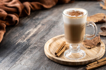 Maple Latte with Cinnamon in Glass Mug on wooden table. Copy space