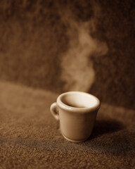 Sepia-toned cup of steaming coffee on textured surface – evokes warmth, calm, and vintage aesthetics. Ideal for morning rituals, cafés, or cozy lifestyle branding.