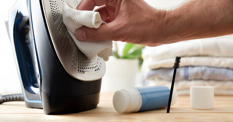 Person cleaning steam iron with rags and industrial products