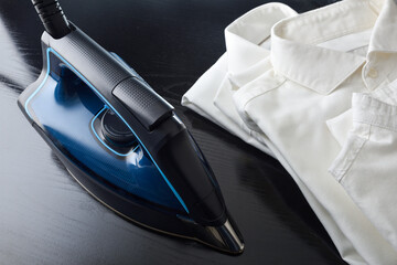 Steam ironing concept with stack of shirts on table top
