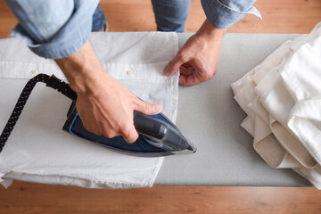 Detail of man ironing shirt on ironing board top view