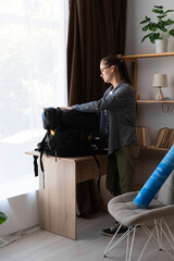 female hiker preparing for mountain hike packing backpack and equipment in living room of her...