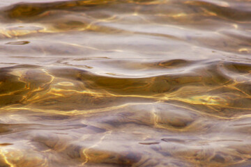 Closeup of waters surface showing motion and movement of small rippling waves of beautiful gold colored lake waters