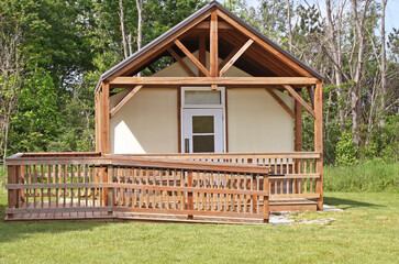 Modern Yurt with canvas walls and wheel chair accessible ramp nestled in a secluded area surrounded by trees and nature