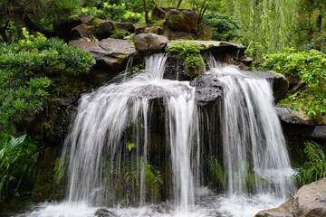 Obraz premium Clear Mountain Waterfall Cascading Through Lush Green Hills Natural Landscape