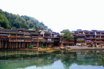 Traditional Hunan Stilted Buildings Over River In Mountain Village Setting
