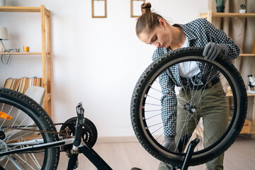 Young woman repairing and servicing her bicycle at home