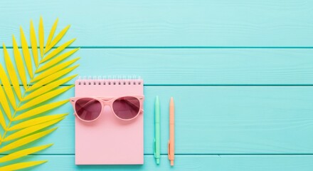 Bright yellow palm leaf and pink accessories on a turquoise wooden background
