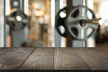 Empty wooden table top and blurred gym or fitness center as background.