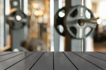 Wooden table surface in foreground with blurred gym background featuring weightlifting equipment....