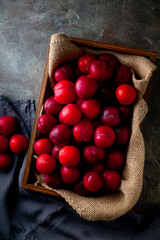 Delicious and Juicy Red Plums.

Vibrant red plums, ripe and ready to eat, arranged in a wooden crate. Ideal for food bloggers and culinary publications.