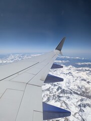 view from airplane window, flying over snow-covered mountains
