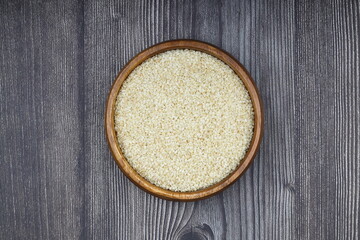 Top view closeup of freshly harvested white sesame in wooden bowl isolated on wooden background...