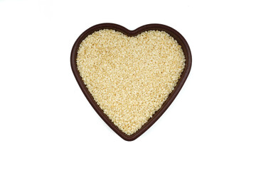 White sesame seeds in a wooden bowl. Top view. A copy of the space. heart-shaped bowl