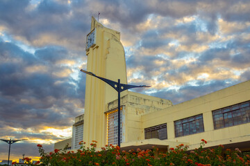 Arquitetura Histórica da Antiga Estação Ferroviária da Cidade de Goiania, atual Museu Frei Confaloni, ao entardecer, com um jardim em primeiro plano.