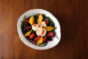 Insalata estiva con burrata, pomodorini, crostini di pane e basilico fresco in una ciotola rustica su tavolo di legno &ndash; piatto italiano fresco e genuino