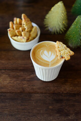Hot latte coffee with latte art and Christmas tree shortbread butter cookies on wooden table