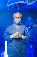 Surgeon ready for surgery. A surgeon stands ready in an operating room, donning blue scrubs and a...