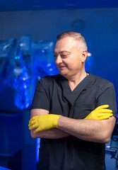 Surgeon getting ready for surgery. A healthcare worker in yellow gloves and black scrubs stands...