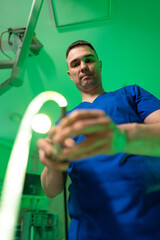 Surgeon readies tools. A healthcare worker in scrubs focuses on a surgical instrument in a brightly...
