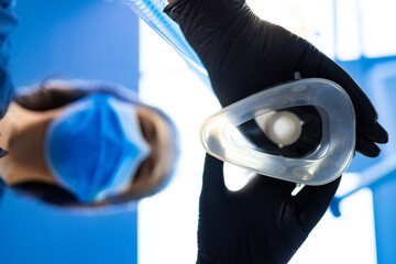 Anesthesia setup by pro. A healthcare professional, wearing gloves and a mask, holds an anesthesia...