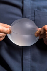 Person holding silicone implant. A person shows the flexibility of a silicone implant, highlighting...