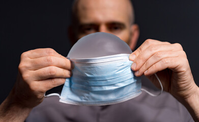 Man preps with a mask on. A man prepares to put on a surgical mask, highlighting health awareness...