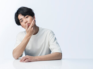 頬に手を当てている若い日本人男性