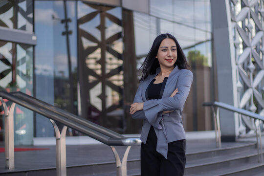 Confident Indian businesswoman walking outdoors with smartphone, smiling joyfully; stylish, professional, elegant, connected, executive, feminine, corporate, trendy, cyberspace, leadership, manager, w