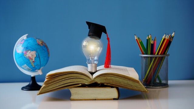 Light bulb with graduation cap on open book, globe and pencils in background
“Global knowledge and academic inspiration – glowing idea bulb wearing mortarboard atop open textbook, learning and educati