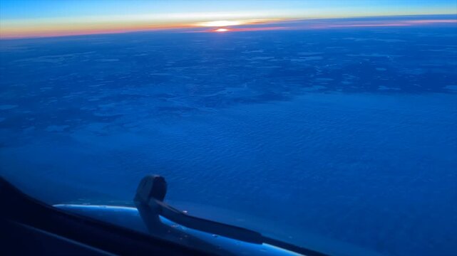 Time-lapse captured from the cockpit of a commercial airliner as the sun rises over the horizon at cruise altitude. The deep blue atmosphere gradually transitions to warm morning light, offering a dra