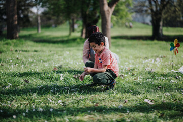 A joyful child picks flowers on a sunny day, enjoying the company of family in a park. The scene...