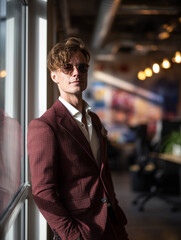 Smiling businessman in burgundy suit holding phone outdoors