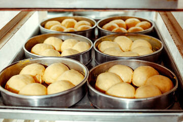 Fresh raw bread dough on the table is in the process of rising before being baked for sale by the bakery.