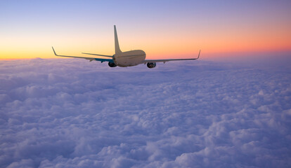 Airplane flying over tropical sea at sunset