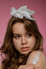 Naklejka premium Woman with Feathers Against a Pink Background