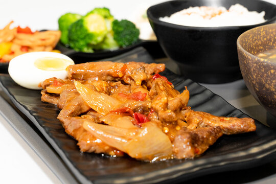 A well-balanced Asian-style set meal served on a tray, featuring tender braised beef strips (Hong Shao Niu Liu) as the main dish, accompanied by a bowl of steamed white rice, three assorted seasonal