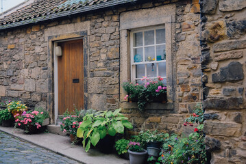 Home decoration with white wooden shutters and wooden door on natural stone wall at small village in Edinburgh, Scotland.