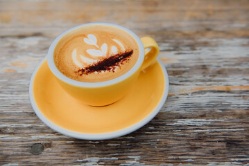 A morning latte on a yellow tray on a classic wooden table.