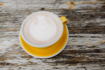 Top view of latte on a yellow tray on a classic wooden table.