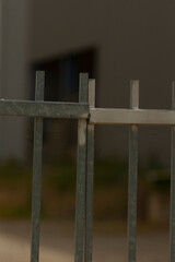 This image features a detailed close up of a sturdy metal fence with an attractive building located...