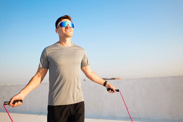 Joyful fitness enthusiast skipping rope at sunrise on a rooftop exercise space