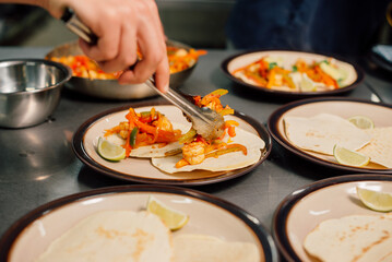 In a vibrant kitchen, colorful shrimp tacos are being meticulously garnished with fresh vegetables...